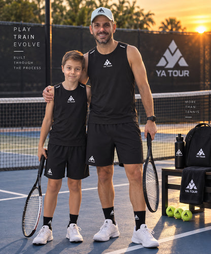 YA TOUR Men's Performance Tank Top – Black, on-model lifestyle shot showing crew neck sleeveless cut with reflective shoulder strap details and YA TOUR logo on chest at outdoor tennis court at sunset