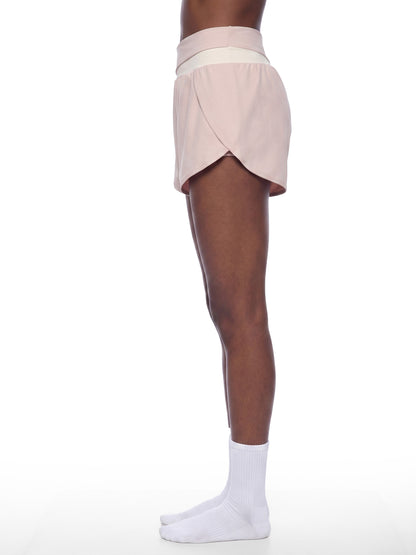 YA TOUR Women's Tennis Panelled Shorts – Light Pink with Apricot, on-model side view showing crossover high-waist waistband, overlay construction and inner liner